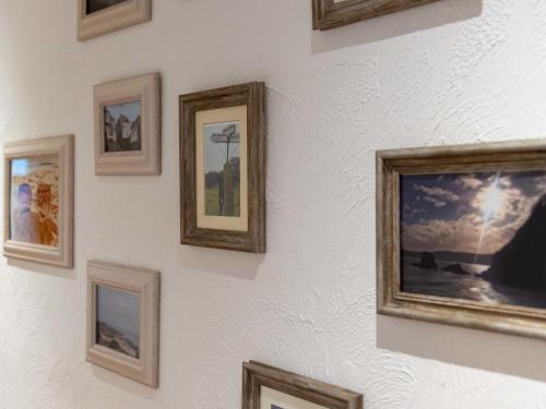 a wall of framed pictures on a white wall at Apartment Lighthouse View by Interhome in Mevagissey