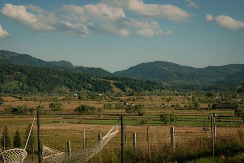 a fence in a field with mountains in the background at Cozy Cube - tiny house in Şarul Dornei