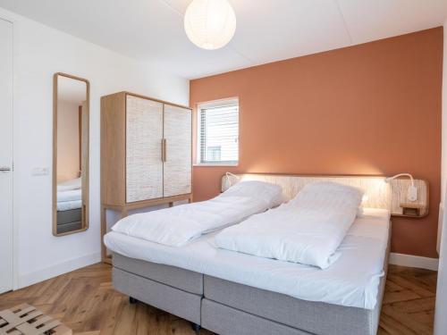 Schlafzimmer mit einem Bett mit weißer Bettwäsche und einem Spiegel in der Unterkunft Holiday Home Duyndomein Noordwijk by Interhome in Noordwijk