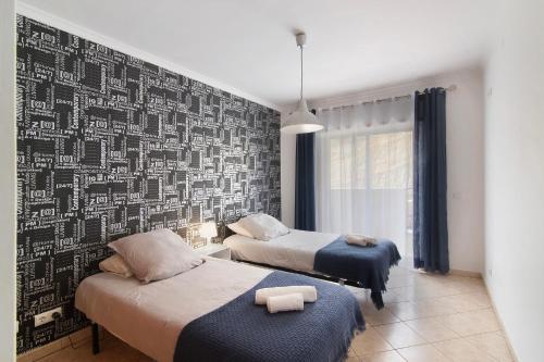 a bedroom with two beds and a black and white wall at Apartamento do Sol in Albufeira