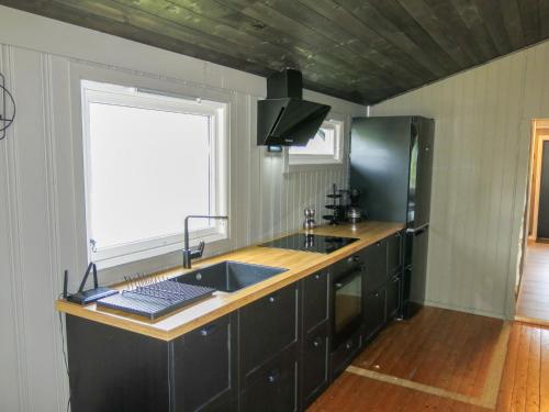 a kitchen with black cabinets and a sink and a window at Holiday Home Bjørnnåslia - SOW161 by Interhome in Åseral