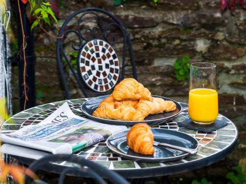 a table with two plates of croissants and orange juice at Apartment Helland by Interhome in Pentewan