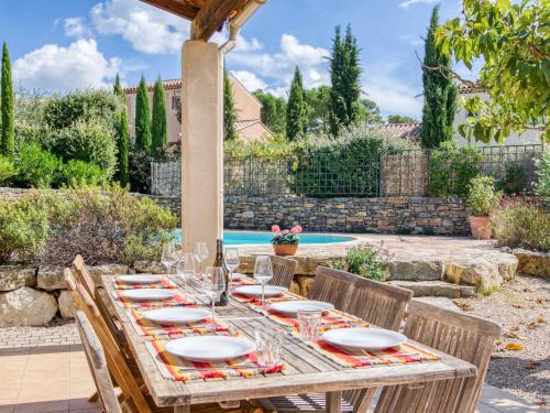 - une table en bois avec des assiettes et des verres dans un jardin dans l'établissement Holiday Home Villa 15 by Interhome, à Nans-les-Pins