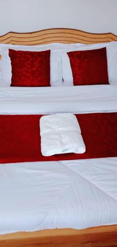 Una cama con almohadas rojas y blancas. en GOLDEN PALM 3, en Nakuru