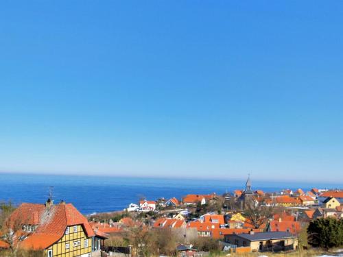 a town with red roofs and the ocean in the background at Apartment Thera - 5km from the sea in Bornholm by Interhome in Gudhjem