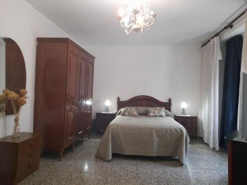 1 dormitorio con cama y lámpara de araña en Casa Mis Abuelos, en Priego de Córdoba
