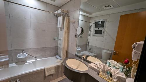 a bathroom with a tub and a sink and a bath tub at City Tower Hotel in Fujairah