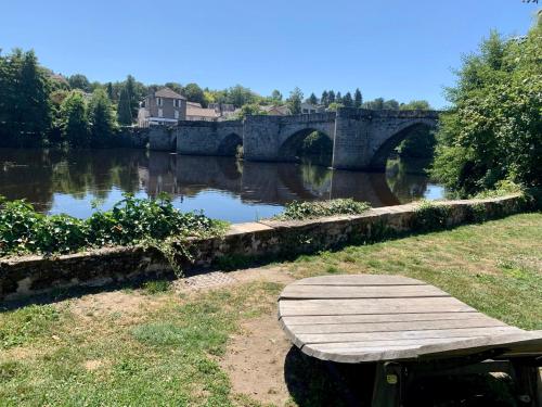 a wooden bench sitting next to a river with a bridge at Studio 2 - Cinéma Sport Parking - DABNB in Limoges
