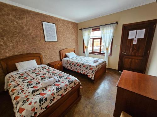 um quarto com 2 camas, uma secretária e uma janela em Hotel Posada de María em Cuenca