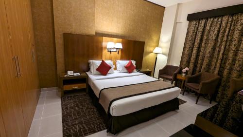 a hotel room with a large bed and a chair at City Tower Hotel in Fujairah