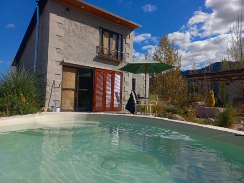 una piscina frente a una casa con sombrilla en Hidden Twins Cabañas de montaña Cacheuta en Cacheuta