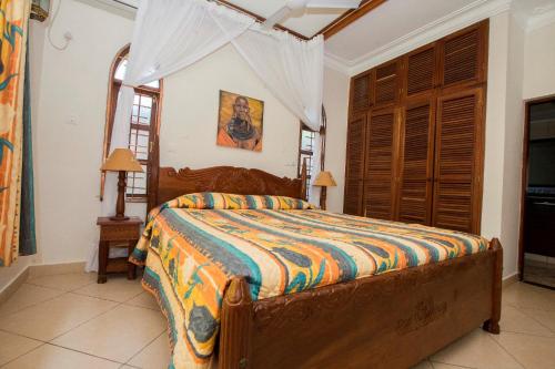 a bedroom with a bed in a room with windows at Diani Pearl in Diani Beach