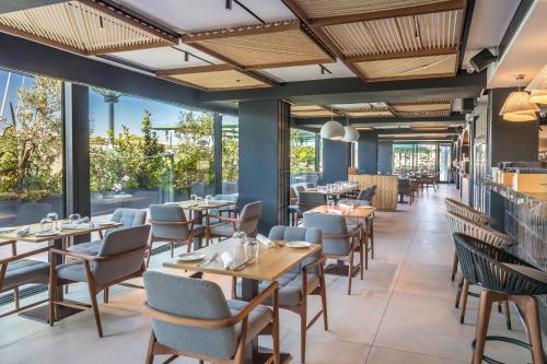 een restaurant met tafels en stoelen en grote ramen bij Barceló Fortina Malta in Sliema