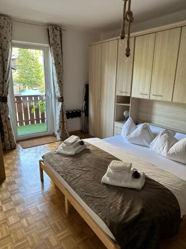 - une chambre avec un grand lit et 2 serviettes dans l'établissement COSTALUNGAHOUSE TrekkingBikeSki selfcheck-in apartment, à Carezza al Lago