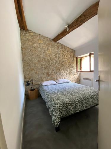 um quarto com uma cama e uma parede de pedra em Villa Baptiste Spa Sauna Billard Piano ping-pong Piscine près de Bordeaux em Cérons