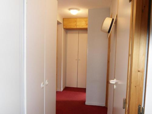 un couloir avec des murs blancs et un sol rouge dans l'établissement Appartement cosy au pied des pistes avec terrasse - FR-1-181-2722, à La Plagne Tarentaise