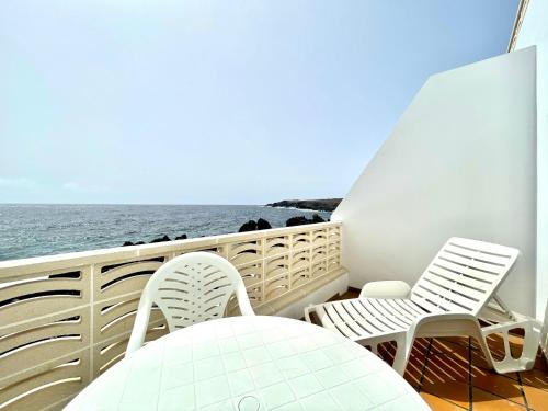 a balcony with chairs and a table and the ocean at Oceanfront apartment a few meters from the beach in Tamaduste