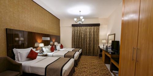 a hotel room with two beds and a television at City Tower Hotel in Fujairah