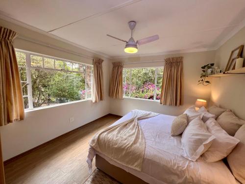 a bedroom with a bed and two windows at Berg Escape Bottlebrush - Spacious Luxury Family Home in Winterton