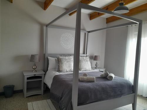 a bedroom with a large canopy bed with two tables at Camelot Cottages in Langebaan
