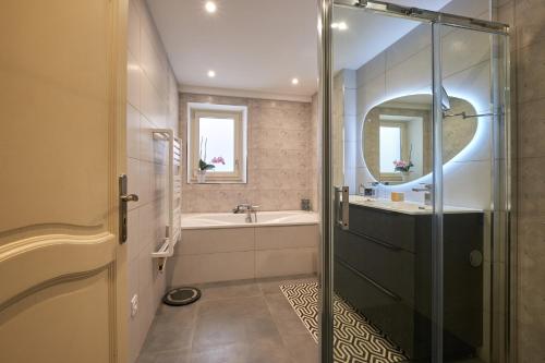 a bathroom with a tub and a sink and a mirror at Maison chez nous in Izeron