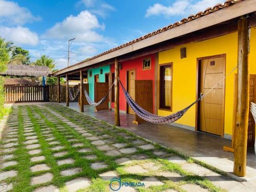 uma casa colorida com uma rede em frente em Pousada Alta Caraíva em Caraíva