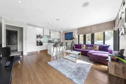 a living room with a purple couch and a kitchen at King beds apartment with en-suite, private balcony and elevator by iconic Portobello Market in London