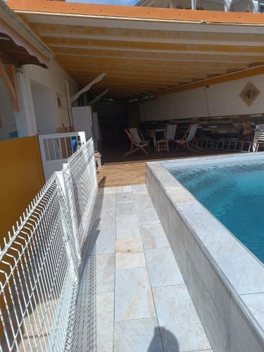 a swimming pool next to a house with a porch at Le Nid De Nicolas in Saint Esprit
