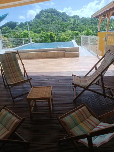 two chairs and a table on a deck with a pool at Le Nid De Nicolas in Saint Esprit