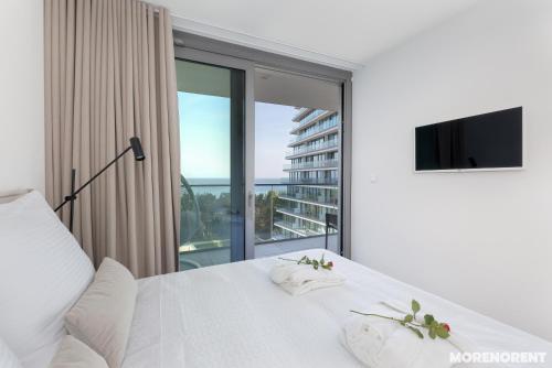 a bedroom with a white bed and a large window at Your Holidays Waves in Międzyzdroje