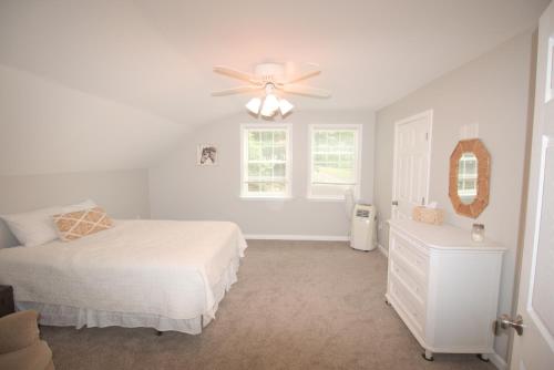 a white bedroom with a bed and a ceiling fan at Mountain Getaway with Lake View in Entriken