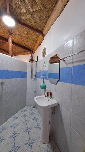 La salle de bains est pourvue d'un lavabo et de carrelage bleu et blanc. dans l'établissement Camiguin Romantic Luxury Stonehouse on Eco-Farm at 700masl, à Mambajao