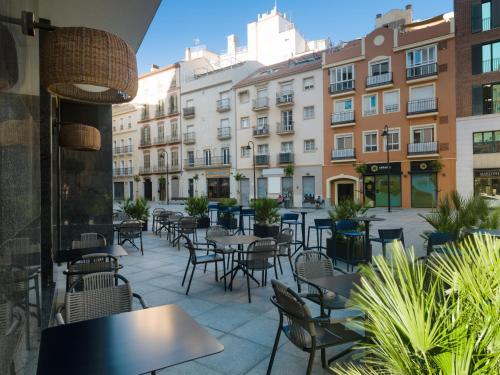 a patio with tables and chairs and buildings at H10 Croma Málaga in Málaga