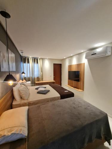a hotel room with two beds and a television at Pousada Maré do Francês in Praia do Frances