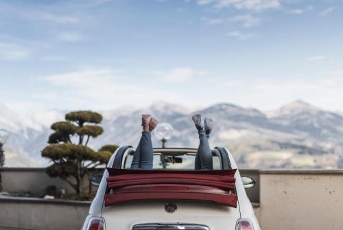 a person sitting in the back of a car with their feet up at Kronplatz-Resort Berghotel Zirm in Valdaora