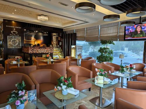 un restaurant avec des tables et des chaises brunes et une télévision dans l'établissement City Tower Hotel, à Fujaïrah