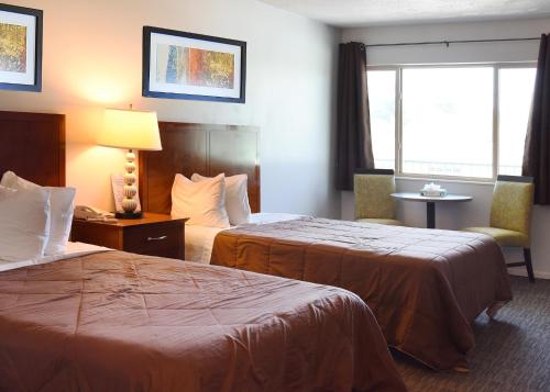 ein Hotelzimmer mit 2 Betten und einem Fenster in der Unterkunft GREELEY UNIVERSITY INN/ GREELEY INN in Greeley