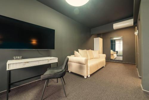 Il comprend un salon doté d'une chaise blanche et d'une télévision à écran plat. dans l'établissement Fullton Central, à Cluj-Napoca
