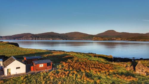 a house on a hill next to a body of water at Harlosh Log Cabins in Dunvegan