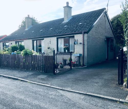 a white house with a fence in front of it at PondeROSEa Cottage Free Gated Parking M1 & City location, wood stove in Lisburn