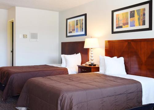 a hotel room with two beds and a lamp at GREELEY UNIVERSITY INN/ GREELEY INN in Greeley