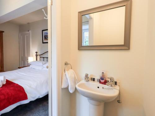 a bathroom with a sink and a bed with a mirror at 6 Calgarth View in Windermere