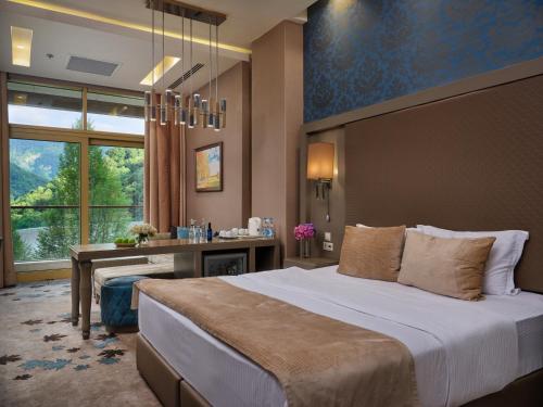 a bedroom with a large bed and a desk and a window at Qafqaz Tufandag Mountain Resort Hotel in Gabala