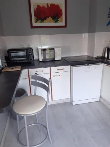 - une cuisine avec une chaise et un four micro-ondes dans l'établissement les jardins du casino, à Saint-Quay-Portrieux
