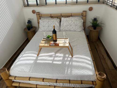 uma cama com uma mesa com uma garrafa de vinho e copos em הסוויטה הפנורמית - Panoramic Suite em Nurit