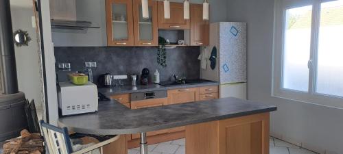 une cuisine avec des armoires en bois et un comptoir dans l'établissement Charmante petite maison, à Torcenay