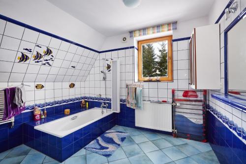 ラプカにあるDrewniany Dom Rabka Zdrójの青と白のバスルーム(バスタブ付)、窓が備わります。