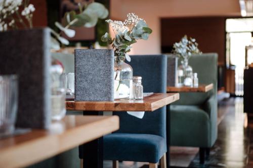 a table with blue chairs and a vase of flowers at Bio-Berghotel Ifenblick in Balderschwang
