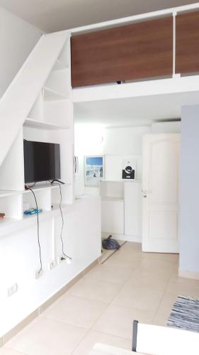 a living room with white walls and a staircase with a tv at Encanto Fueguino calido centrico wifi para dos in Ushuaia