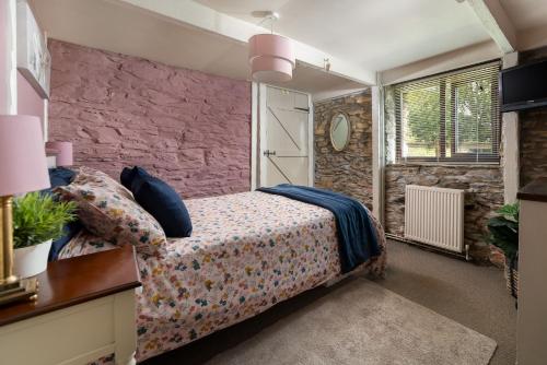 a bedroom with a bed and a stone wall at The Shippen at Fowey in Fowey